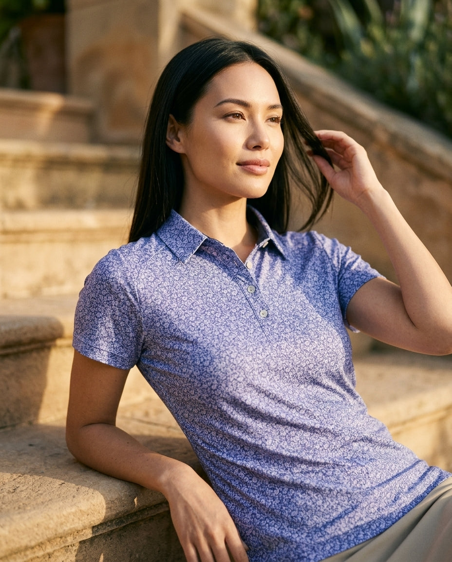 Woman in lavender floral NIAM polo seated on warm stone terrace steps